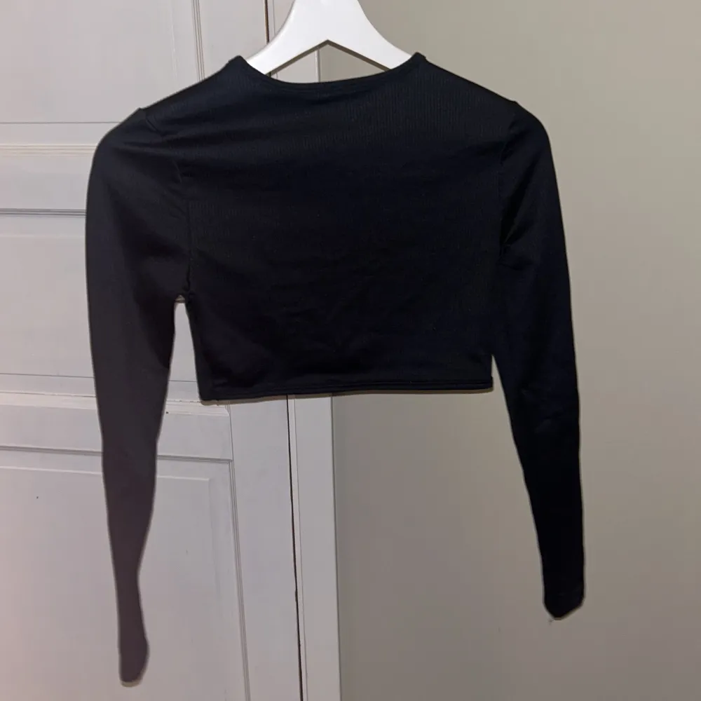 Snygg svart croppad topp från H&M Divided i storlek S. Den har långa ärmar och en enkel design som passar perfekt till både vardag och fest. Toppen är i ett mjukt och stretchigt material för en bekväm passform.. Yläosat.