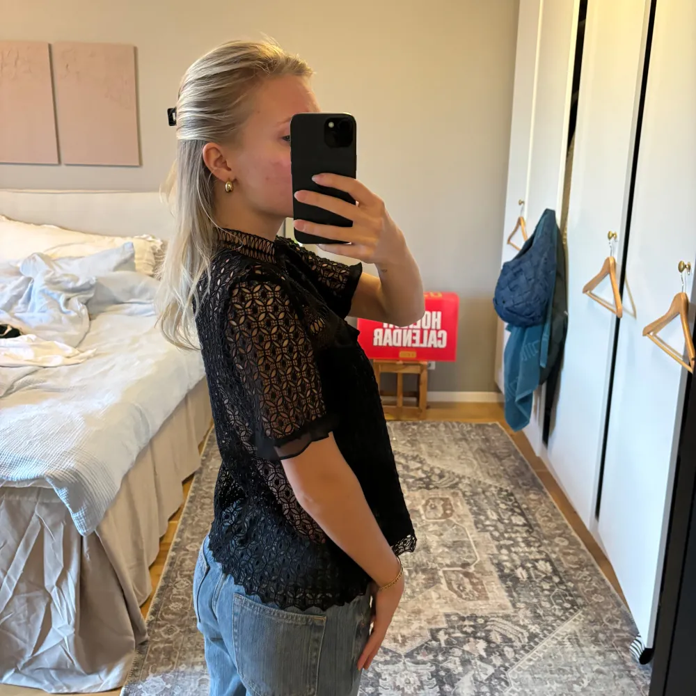 Säljer en elegant svart spetsblus med korta ärmar och hög hals. Blusen har ett vackert mönster och är perfekt för en festlig kväll. Den är lätt och luftig, vilket gör den bekväm att bära. Passar bra till både jeans och kjol för en chic look.. Yläosat.