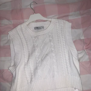 Vit stickad väst - Säljer en superfin vit stickad väst med flätmönster. Perfekt för lager-på-lager under höst och vinter.