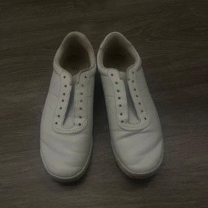 Vita sneakers utan snören - Säljer ett par vita sneakers i syntetmaterial. De har en stilren design utan snörning, vilket ger en minimalistisk look. Perfekta för vardagsbruk och passar till det mesta i garderoben. Skostorlek dam 39 💓