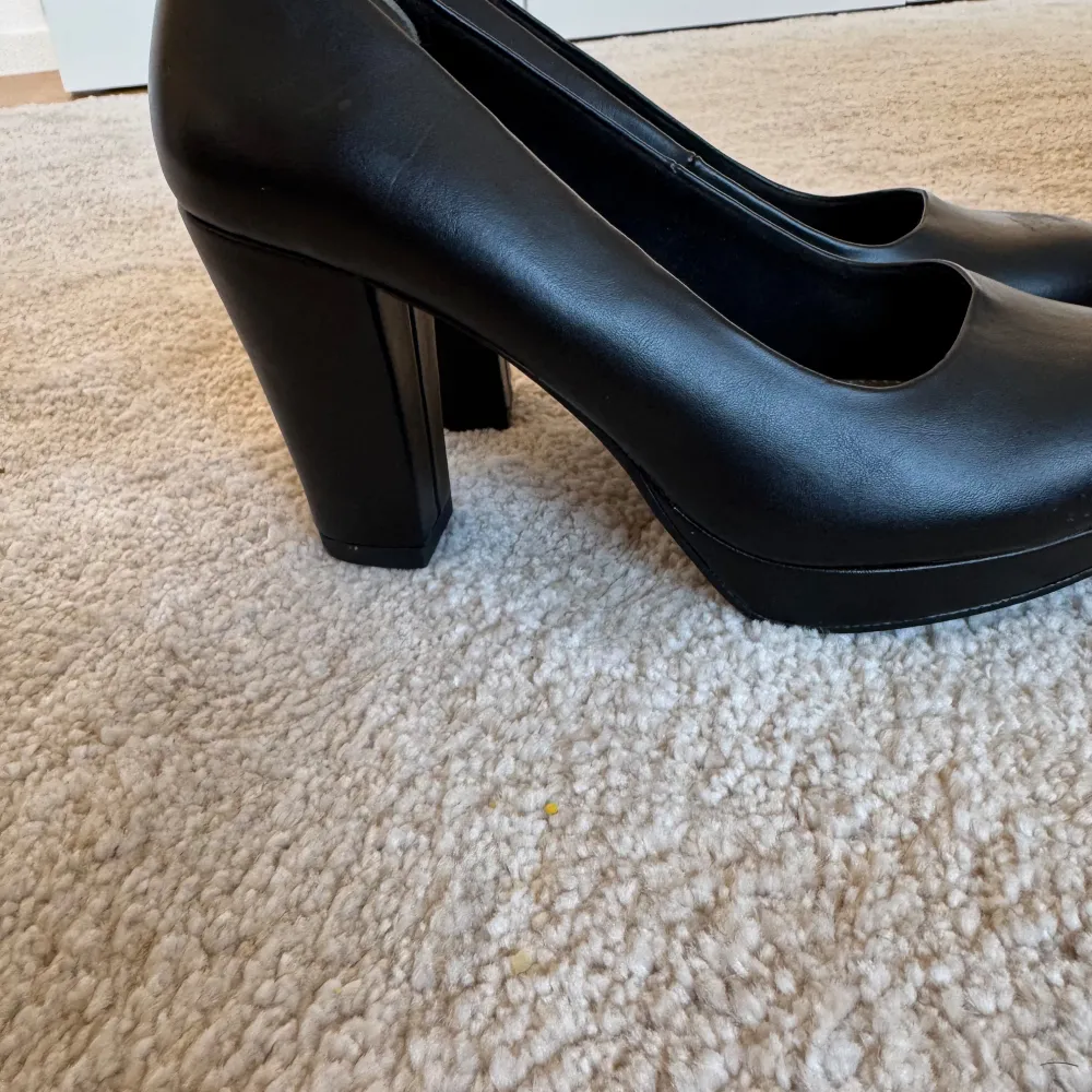 Snygga svarta pumps i skinn med hög klack. Perfekta för fest eller en elegant kväll ute. De har en klassisk design med rundad tå och är i mycket bra skick. Storlek dam 38.. Skor.