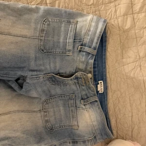 Ljusblå jeans från Madlady - Säljer ett par ljusblå jeans från Madlady i storlek EU 36. De har en snygg bootcut-stil och är lowwaist med dragkedja och knapp framtill. Dom har tappa en knapp på bakfickan därav priset!
