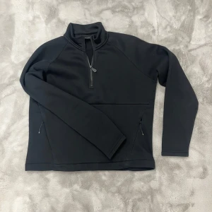 Svart zip up från Sail Racing - Säljer en svart zip up tröja från Sail Racing i mycket bra skick. Den har en halv dragkedja framtill och två praktiska fickor med dragkedjor. Perfekt för kyliga dagar och passar bra till både vardag och träning. Storleken är i XL för barn men passar M.