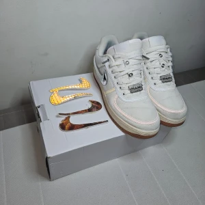 Nike Air Force 1 Travis Scott - Säljer ett par Air Force 1 Travis Scotts med utbytbara swooshes i olika färger och mönster. Skorna har en klassisk design med snörning och en bekväm gummisula. Perfekta för att ge din outfit en unik touch! De är i mycket bra skick och kommer med originalkartong.
