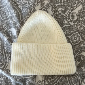 Vit stickad mössa - Säljer en superfin vit stickad mössa i nytt skick. Den är ribbad och perfekt för kalla vinterdagar. Mössan är mjuk och bekväm, och passar de flesta tack vare sin flexibla passform. Ett måste för vintern! ❄️från lager157 och helt oanvänd 