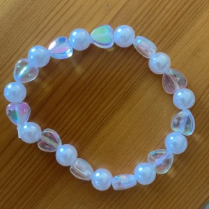 Whitecoz🤍 - Säljer ett supergulligt armband med vita pärlor och genomskinliga hjärtformade pärlor som skimrar i regnbågens färger ”whitecoz🤍”. Perfekt för att ge en söt touch till din outfit! Passar både till vardags och festliga tillfällen💗40kr