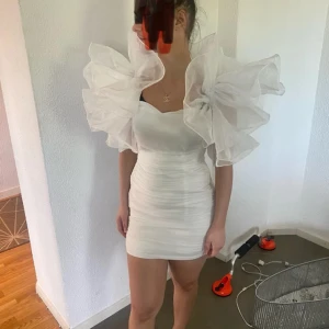Vit kortklänning med stora puffärmar - Säljer en superfin vit kortklänning med stora, dramatiska puffärmar. Klänningen är tight och perfekt för fest eller student. Den har en elegant och unik design som verkligen sticker ut. Materialet känns lyxigt och klänningen sitter som en dröm. Perfekt för dig som vill göra ett statement!