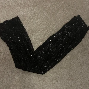 Festbyxor - Snygga svarta byxor från New Yorker i storlek XS. De är täckta med glittriga paljetter, perfekta för festliga tillfällen. Byxorna har en tight passform och är gjorda i ett syntetmaterial och är superstretchiga så passar en S också. Använd bara en gång men kan ha några lösa trådar 