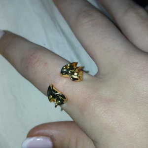 Guldfärgad ring med fiskdesign - Säljer en unik guldfärgad ring med en cool fiskdesign. Ringen är öppen och justerbar, vilket gör den lätt att anpassa till olika fingerstorlekar. Perfekt för att ge en touch av havsinspiration till din outfit. 🐟✨