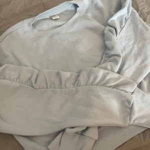 Ljusblå tröja med volanger på ärmarna från Lindex  - Fint använt skick. St 158/164. Säljer pga nästan aldrig använd. Ganska liten i storleken