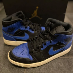 Nike Air Jordans i svart och blått - Säljer ett par snygga Nike Air Jordans i svart och blått. Skorna har en klassisk design med snörning och en bekväm passform. Perfekta för både vardag och fest! De är i mycket bra skick och redo för nya äventyr. I storlek 42,5