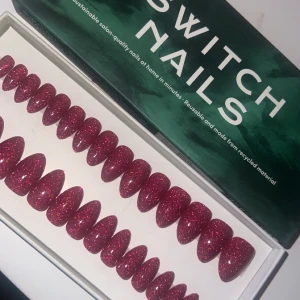 Glittriga lösnaglar från Switch Nails - Snygga och hållbara lösnaglar i en härlig röd nyans med massor av glitter. Perfekta för en festlig look! De är återanvändbara och gjorda av återvunnet material, vilket gör dem både miljövänliga och praktiska. Lätta att applicera och ger en salongskvalitet hemma.