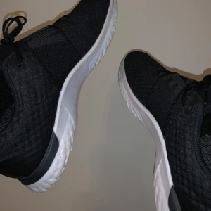 Svarta Nike sneakers - Säljer ett par svarta Nike sneakers i mycket bra skick. De har en vit sula och klassisk Nike-logga på sidan. Skorna har snörning och ovanpå ett Nike band.