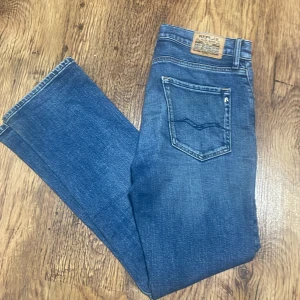 Blå jeans från Replay - Säljer ett par snygga blå jeans från Replay i bra skick men har hål i högra fickan men man kan bara sy ihop. De har en klassisk femficksdesign och en draggylf. Perfekta för vardagsbruk och kan enkelt matchas med olika outfits. Modell Thad. Priset är ej hugget i sten. Hör av vid frågor och funderingar!