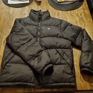 Svart pufferjacka från Dickies - Säljer en svart pufferjacka från Dickies i storlek S. Jackan har en dragkedja framtill och är perfekt för kyliga dagar. Den är i mycket bra skick och har långa ärmar. Perfekt för höst och vinter!
