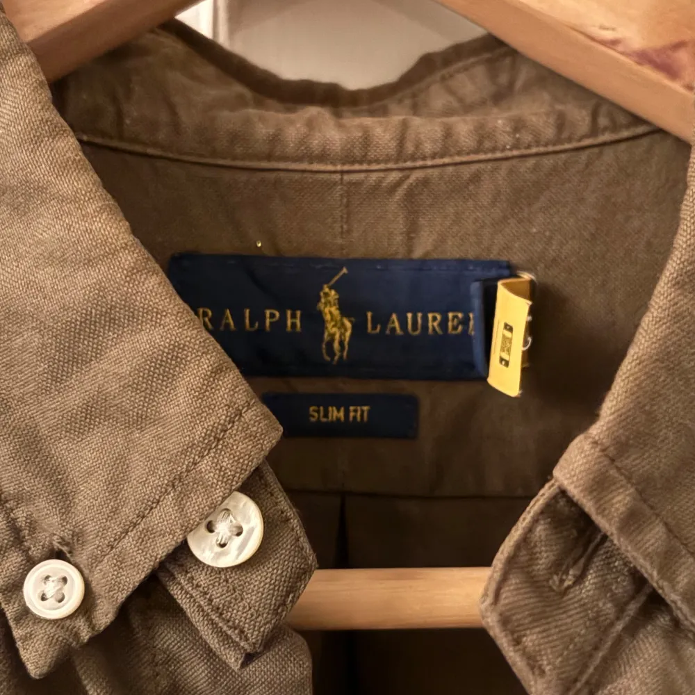 Säljer en snygg olivgrön skjorta från Ralph Lauren i slim fit. Skjortan har långa ärmar och klassiska knappar framtill. Perfekt för både vardag och fest! 🕺. Skjortor.