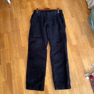 Svarta manchesterbyxor från Urban Classics - Säljer ett par svarta manchesterbyxor från Urban Classics i storlek 30. Byxorna har en klassisk rak passform och är perfekta för höst och vinter. De är i nytt skick med etiketten kvar. Perfekta för en stilren och bekväm look!
