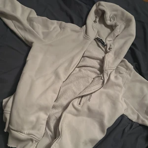 Grå fleecejacka med huva - Mysig grå fleecejacka från Didriksons med huva och dragkedja. Perfekt för kyliga dagar och passar bra till vardags. Jackan har en normal passform och är i mycket bra skick.