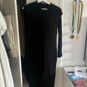 Svart stickad klänning onesize  - Säljer en svart stickad klänning i mycket bra skick. Den är ärmlös och har ett snyggt ribbat mönster som ger en stilren look. Perfekt för höst och vinter, och kan enkelt stylas med en långärmad tröja under för extra värme. Passar både till vardags och festligare tillfällen.