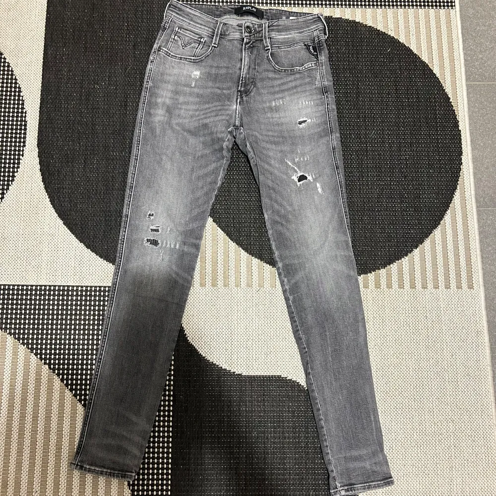 Säljer ett par grå Replay jeans i slim fit. De är tillverkade av ekologisk bomull och har en snygg slitning för en cool look. Perfekta för både vardag och fest! 🖤. Jeans & Byxor.