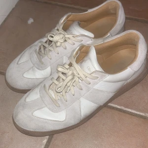 Oliver Cabell Gats - Säljer ett par vita sneakers i bra skick med snygga mockadetaljer som liknar maisons margielas gats. Passar till det mesta i garderoben. Skick är 7/10 Dom är köpta för 3000.