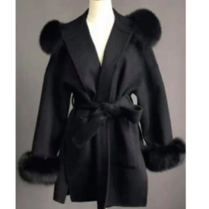 Svart kappa med pälsdetaljer - Snygg svart kappa med lyxiga pälsdetaljer på axlar och ärmslut. Den har en elegant knytning i midjan som ger en fin siluett. Perfekt för höst och vinter när du vill vara både varm och stilren. Passar lika bra till vardags som till festliga tillfällen. Man kan ta av pälsen på armarna ifall man skulle vilja det. Använd under 1 vinter och kommer inte till användning nån mer. Köptes för 1899kr men säljer för 700kr kan gå ner i pris vid snabb affär.