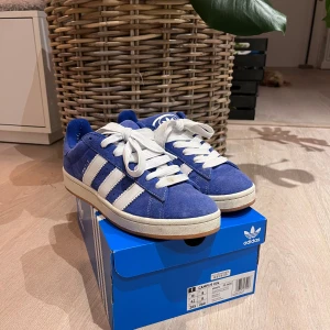 Blå Adidas Campus sneakers - Säljer ett par snygga blå Adidas Campus sneakers i mocka. Perfekt för en casual look. Går att välja vilken snörning man vill ha så fixar jag! (Se bild 2 och 3). Skorna är i nytt skick då de är använda bara ett fåtal gånger och kommer i originalbox, två extrasnören tillkommer. Ny pris ca 1300, finns kvitto, mitt pris: 550, går att sänka vid snabb affär. Det är bara att fråga över minsta lilla fundering!