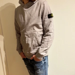 Stone Island hoodie  - Ljusgrå hoodie från Stone Island, storleken är junior men passar perfekt på någon som har S