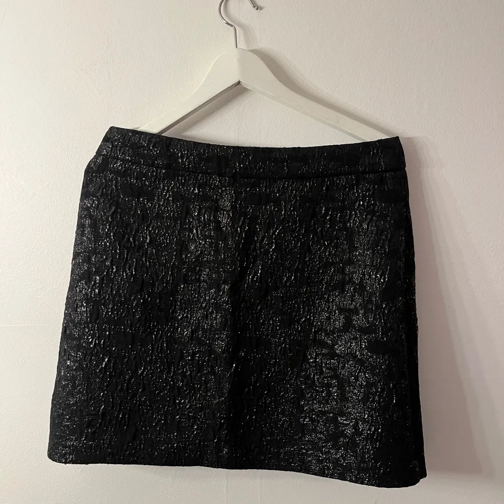 Säljer en superfin svart glittrig kjol som är perfekt för festliga tillfällen. Den har en elegant och stilren design med en kort längd som passar perfekt till både vardag och fest. Kjolen är i mycket bra skick och ger en lyxig känsla med sitt glittriga material. Har även sätt att många använder kjolen till topp vilket också är så fint❣️kjolen har ingens stretch vilket kan göra att den upplevs liten.. Hameet.
