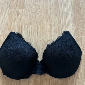 Svart spets-bh - Säljer en elegant svart bh med spetsdetaljer. Den har en vacker blommig spetsdesign och justerbara axelband för perfekt passform. 💖 Helt oanvänd!