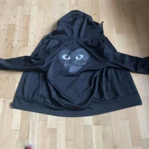 Svart hoodie med tryck - Säljer en svart cdg hoodie . Den har dragkedja fram och en skön huva. Perfekt för höst och vår, och passar till både chill och casual outfits. Den är i bra skick och redo för nya äventyr! Storlek m men sitter som s