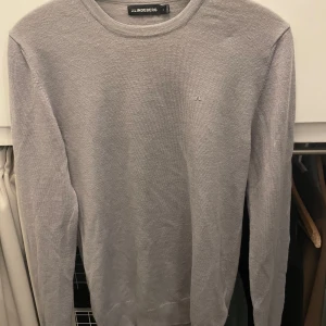 Grå tröja från J.Lindeberg - Säljer en stilren grå tröja från J.Lindeberg i mycket bra skick. Den är perfekt för både vardag och lite finare tillfällen. Tröjan har en diskret logga på bröstet och är gjord i ett mjukt material som känns skönt mot huden. Passar perfekt till höst och vår!