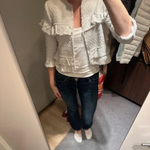 Vit volangjacka - Säljer en superfin vit jacka med volangdetaljer. Den har trekvartsärmar och en härlig struktur i materialet. Perfekt för vår och sommar när du vill ha något lätt och stilrent. Passar både till vardags och fest!