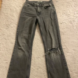 Grå jeans med slitningar - Säljer ett par midwaist jeans från ginatricot, hål i ena knät. Klippta så det passar mig som är 1,64 lång. 