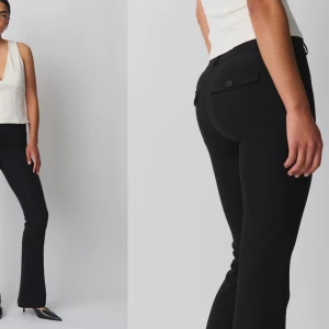 Svarta byxor med knappar - Säljer ett par stilrena svarta byxor med knappar bak. De har en bootcut-stil som ger en snygg siluett. Perfekta för både vardag och fest! Dem är helt nya har aldrig använt. Vet att det är för små i längden eftersom att jag är 174. Passar folk(145-165)