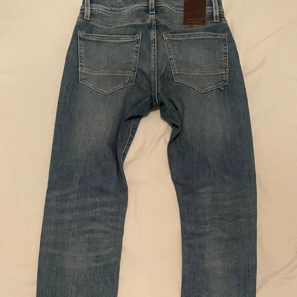 Säljer ett par snygga blå jeans från Jack & Jones i modellen Slim/Glenn. De har en cool slitning på framsidan som ger en avslappnad look. Perfekta för både vardag och fest! 🕺 Inga defekter, som ny. Priset kan diskuteras. NYPRIS - 739kr. Jeans & Byxor.