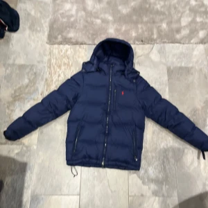 Mörkblå dunjacka - Säljer en snygg mörkblå dunjacka från Ralph Lauren. Den är för liten för mig nu men riktig go kvalite och väldigt snygg. Säljer den billigt priset kan diskuteras men inte mycket. Köpte den för runt 4500kr så sjukt bra pris