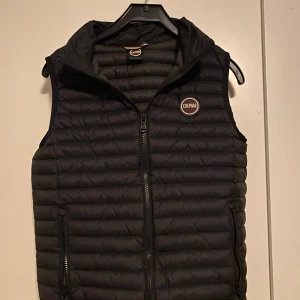 Svart dunväst från Colmar - Säljer en snygg svart dunväst från Colmar i mycket bra skick. Västen har en dragkedja framtill och är perfekt för höst och vår. Den är quiltad och har en normal passform. Perfekt för lager-på-lager-stil!