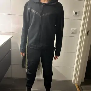 Säljer en svart hoodie från Nike i bra skick. Den har en dragkedja framtill och en bekväm passform. Perfekt för höst och vinter, med långa ärmar och en klassisk design. Passar både till träning och vardagsbruk. Underdel och överdel båda i storlek s! Andra generationen så finns inte att köpa längre. Köpt för 2100! Säljs för 1400 för båda delar! SPARSAMT ANVÄND!