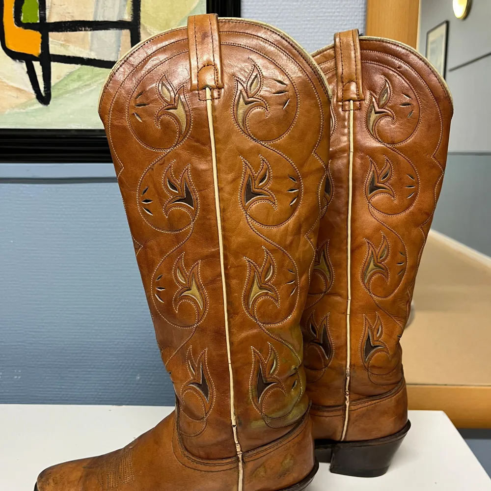 Säljer ett par snygga bruna cowboy boots i skinn med coola broderade mönster. De har en robust klack och är i bra skick, perfekta för både vardag och fest. Sulorna är svarta och ser slitstarka ut. Passar perfekt för höst och vår!. Skor.