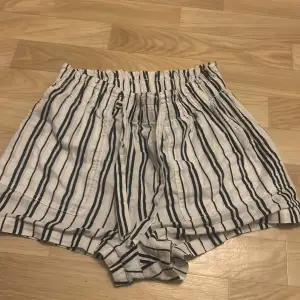 Säljer ett par superbekväma randiga shorts från H&M i vitt och svart. De har en elastisk midja med knytband för extra komfort. Perfekta för varma sommardagar eller en avslappnad dag hemma. 🖤🤍