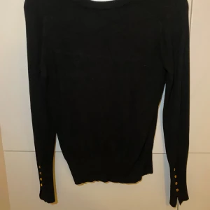 SVART STICKAD MED GULDKNAPPAR  - Svart stickad från ZARA, tunn men varm. Guldknappar på ärmens slut & även en liten slits. 