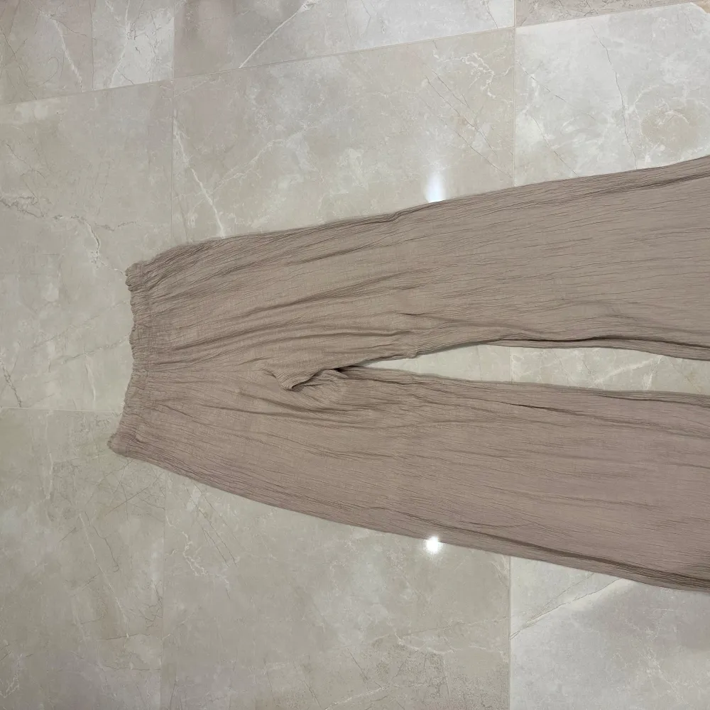 Säljer ett par superbekväma beige byxor från Zara i storlek S. De har en loose fit och är gjorda i ett lätt och luftigt material, perfekt för varma dagar. Byxorna har en elastisk midja för extra komfort. Perfekta för en avslappnad stil!. Jeans & Byxor.