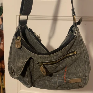 Grå väska  - Grå väska med massa dragkedjor och detaljer🤗Bandet är justerbart och den har många olika fack. Pyttelite sliten på vissa ställen tex på baksidan, men inget som märks av. Kan skicka fler bilder privat 🙌🏻🙌🏻 