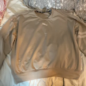 Beige sweatshirt från Stronger - Säljer en snygg beige sweatshirt från Stronger i storlek L. Den är gjord av 90% polyester och 10% elastan, vilket gör den både bekväm och stretchig. Perfekt för en avslappnad stil eller träning. Använd ett fåtal gånger, så den är i mycket bra skick.