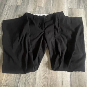 Svarta kostymbyxor  - Säljer ett par svarta kostymbyxor i bra skick. De är midwaist och har en loose passform, vilket gör dem superbekväma för både vardag och fest. Perfekta för höst och vinter då de är gjorda i ett tjockare material. Passar till allt och är ett måste i garderoben!