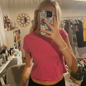 Rosa babytee - Säljer en superfin rosa croppad t-shirt i bra skick. Perfekt för sommardagar eller en avslappnad look. T-shirten har en enkel design med korta ärmar och är gjord i ett mjukt material. Passar perfekt till jeans eller kjol!