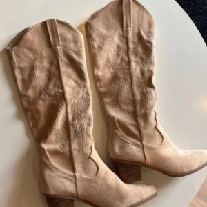Beige cowboy boots - Säljer mina cowboy boots då de inte kommer till användning längre, Inköpta för ca 500kr mitt pris 250 eller bud med rätt att neka. Finns en liten liten deffekt längst fram på spetsen