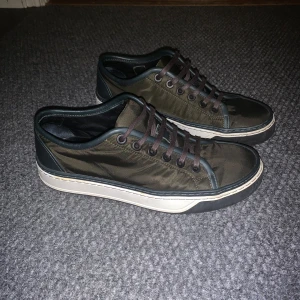 Olivgröna sneakers från Lanvin - Säljer ett par olivgröna sneakers från Lanvin i mycket bra skick. De har en stilren design med snörning och en vit sula som ger en snygg kontrast. Perfekta för både vardag och fest! 🥳
