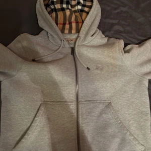 Grå Burberry Tröja - Säljer en Burberry tröja på grund av att den blivit för liten, använd ett tiotal gånger och är i bra skick! Finns inget kvitto, därav priset. 